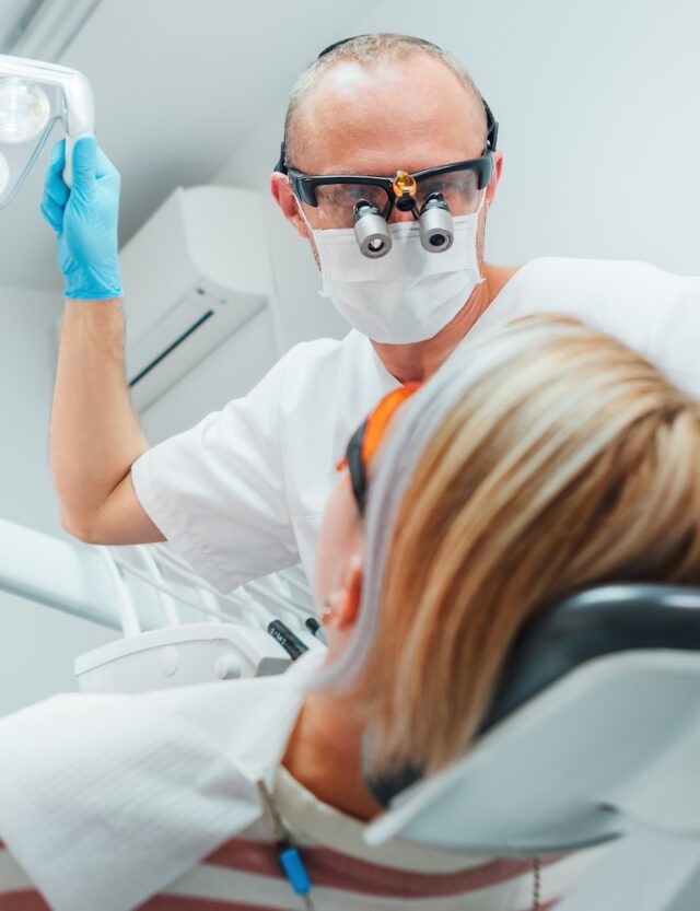 Dental,Clinic,Patient,Appointment.,Dentist,Man,In,Magnifying,Glasses,Pointing