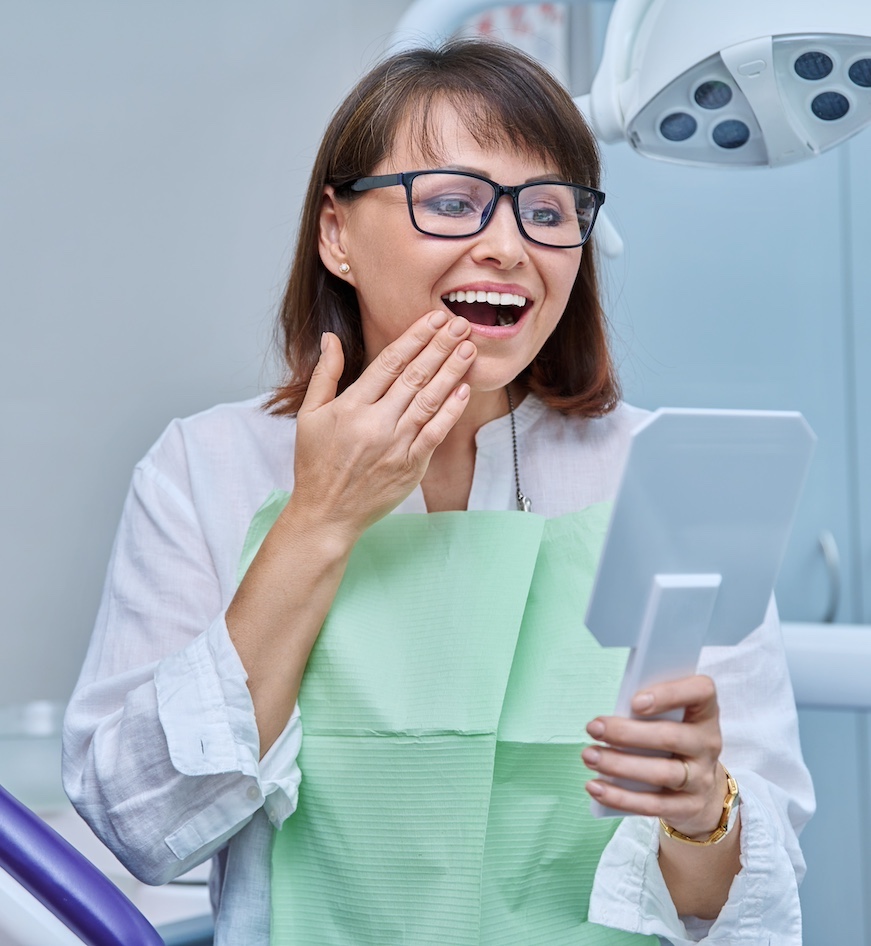 Middle-aged female in dental office looking in mirror