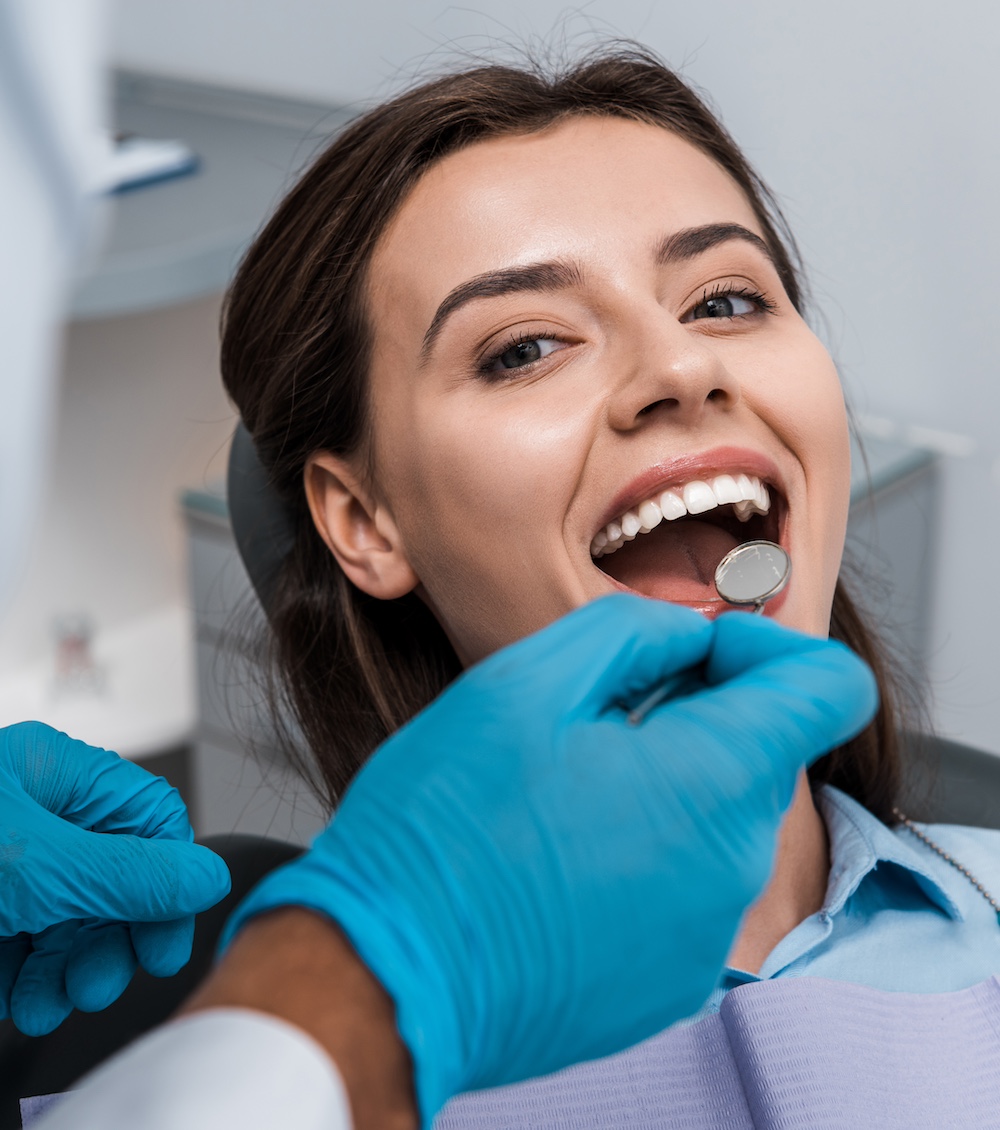 selective focus of dentist in latex gloves holding dental mirror near woman