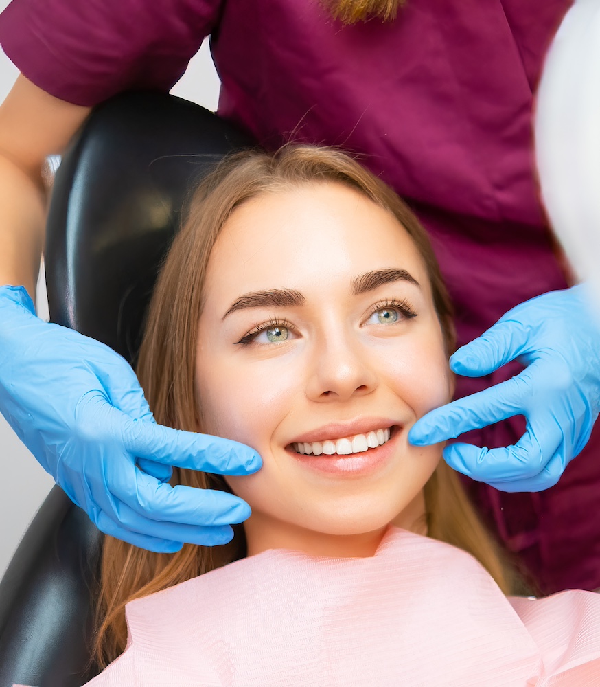 Dentist demonstrates the perfect smile of the patient after implatation of dental veneers or teeth whitening.